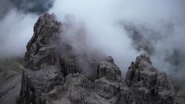 Dramatic mountain peaks shrouded in mist, showcasing rugged terrain and cloudy skies
