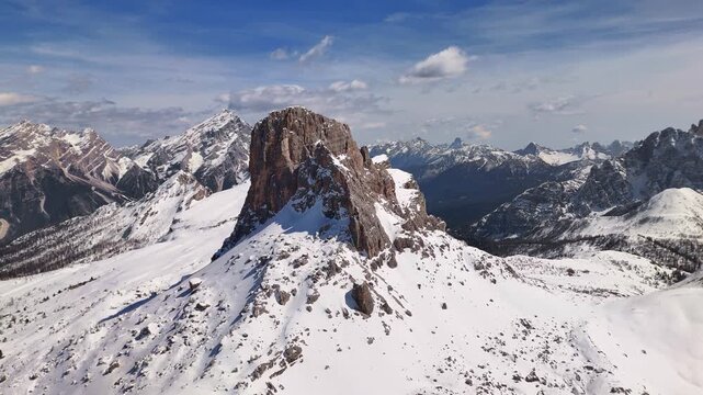 Drone approaching iconic Dolomite pinnacle of Becco del Mezzod&Atilde;&not; with snow fields and distant Antelao, Cortina, Italy