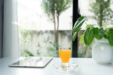 Orange in a glass cup and tablet and philodendron plant © paladin1212