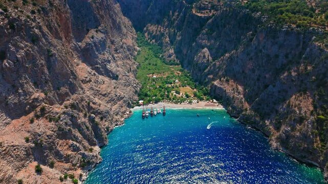 Drone view of Butterfly Valley, Turkey between cliffs. Turquoise bay, rocky canyon walls and green valley create a famous Mediterranean travel view.