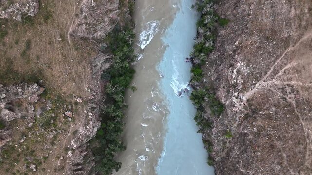Aerial of milky turquoise Chu River flowing through red rock canyon in Boom Gorge, Kyrgyzstan