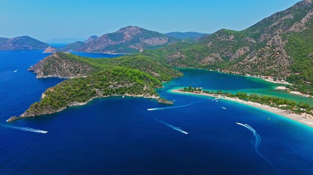 Aerial view of Oludeniz Beach, Turkey bay and mountains. Boats and ships float on deep blue water near green hills and coastline.