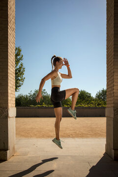 Determined woman doing high knees workout in sunny park