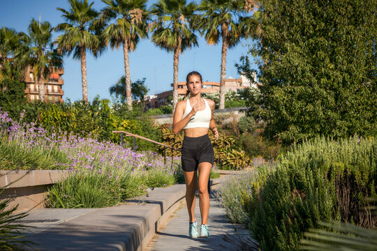 Woman jogging in sunny park showing resilience and effort