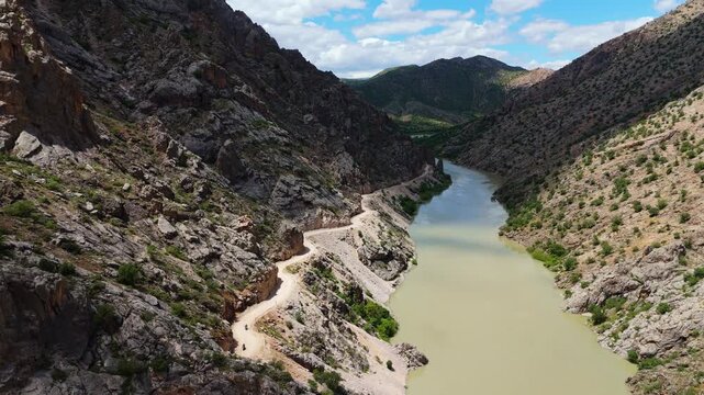 Wide aerial view of the historic Kemaliye Stone Road winding along the steep cliffs of Dark Canyon, Turkey. Drone shot of the famous hand-carved mountain path by the Karasu River