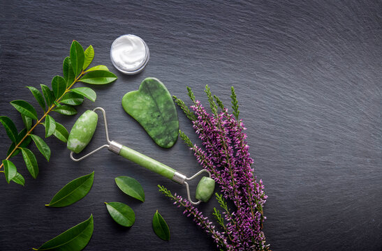 Spa skincare flat lay with jade roller, gua sha and flower