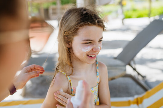 Mother applying sunscreen on daughters face.