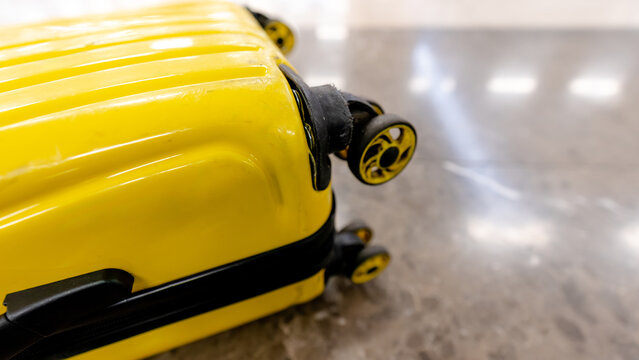 Broken yellow suitcase close up on airport floor travel