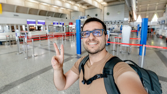 Smiling traveler taking airport selfie in empty check-in hall