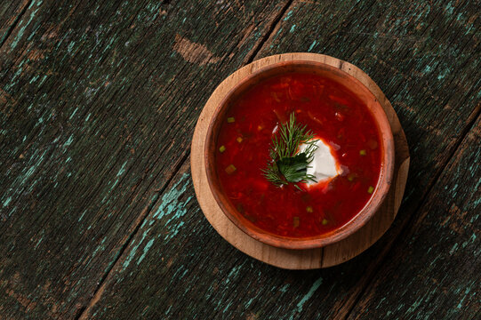 Traditional Ukrainian borscht soup with sour cream and dill in a clay bowl