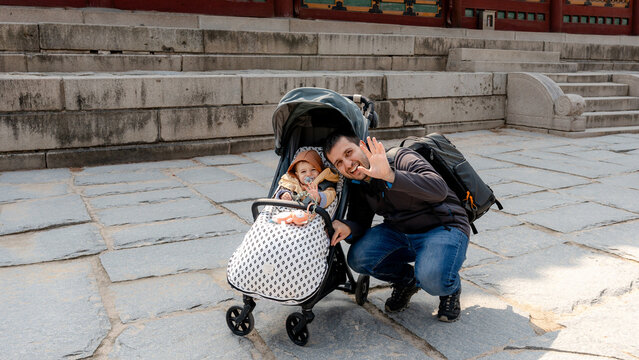 Family with stroller waving in courtyard at Deoksugung