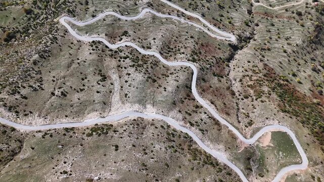 Top-down aerial of serpentine mountain road on steep hillside, Pindus Mountains, Greece