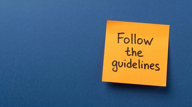 Yellow sticky note with handwritten follow the guidelines text message on dark blue surface guidelines business
