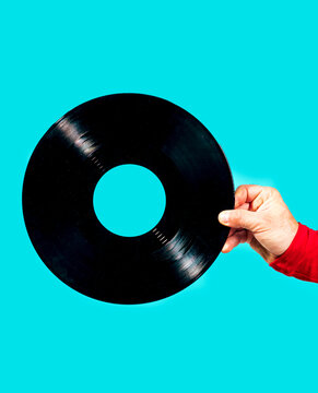 Hand holding vinyl record on turquoise background copy space