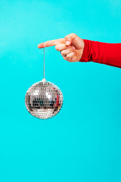 Retro disco ball held on string against turquoise backdrop