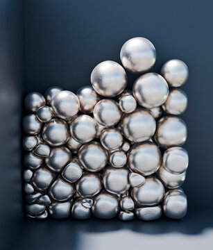 Silver metallic balls stacked in a dark container close-up