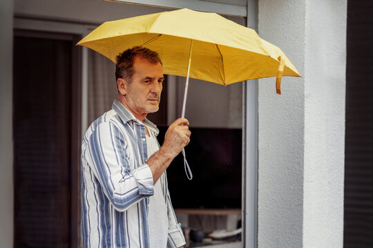 Man holding yellow umbrella in serene contemplation