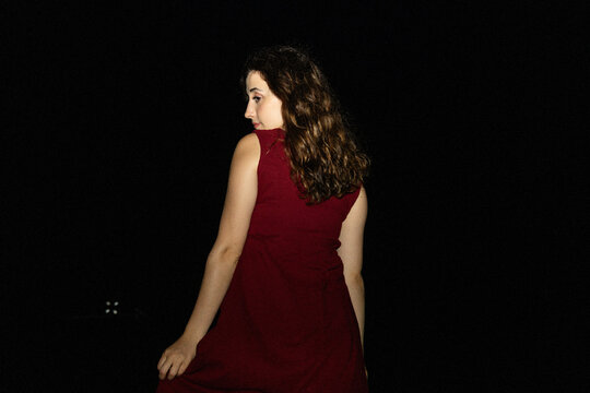 Young woman in red dress under dramatic night spotlight