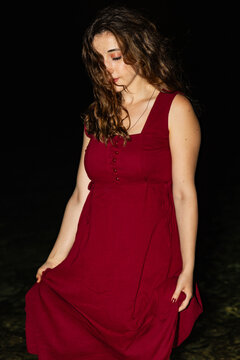 Young woman in red dress posing outdoors at night