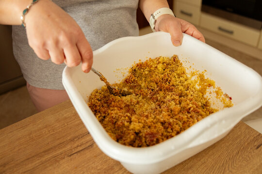 Person mixing bulgur salad in a white bowl at home