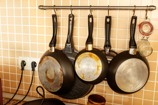 Hanging frying pan set on kitchen wall tile background