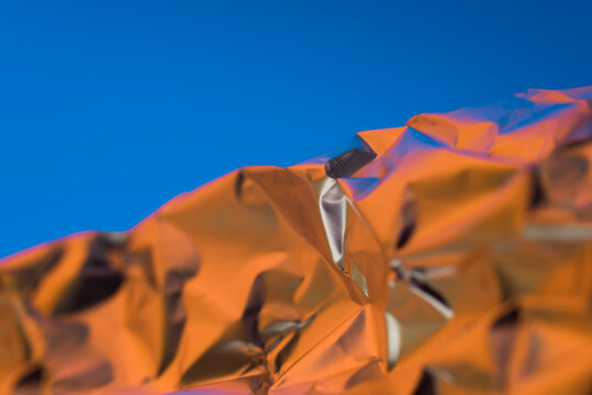 Abstract crumpled foil with blue sky background