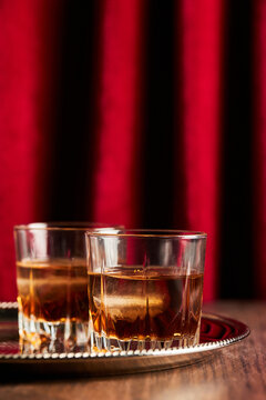 Whisky bourbon in two glasses on tray with red backdrop