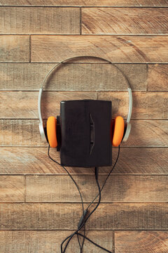 Retro walkman with orange headphones on wood background
