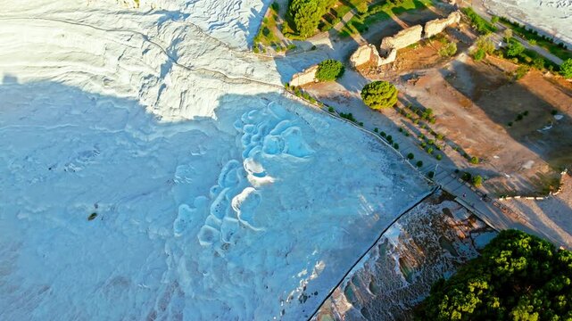 Drone view of Travertines of Pamukkale, Turkey. White mineral terraces, turquoise pools and nearby trees create a natural travel scene.
