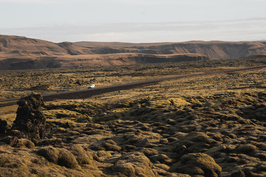 Remote icelandic lava field with lone car on gravel road