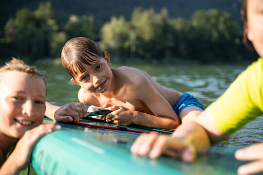 Children playing water games on paddleboard at lake