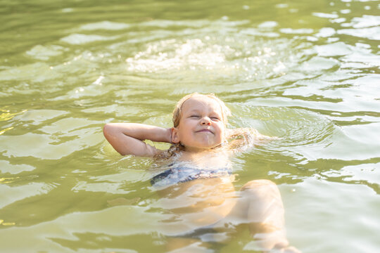 Girl floating in lake water, relaxing on summer vacation