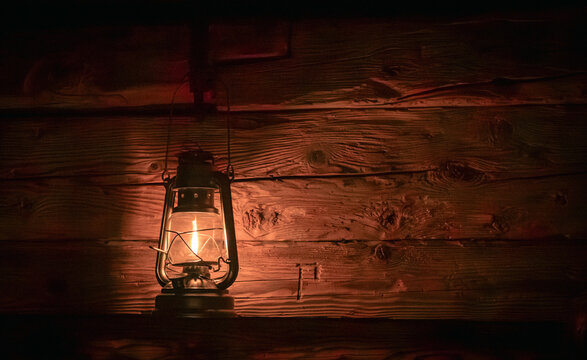 Lantern casting warm glow on wooden wall at night