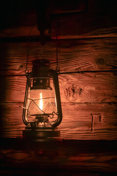 Vintage lantern illuminating wooden wall in darkness