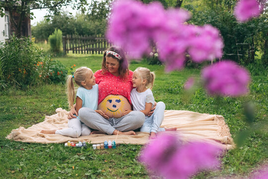 Happy pregnant mother with daughters relaxing in garden