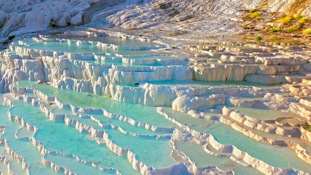 Aerial view of Travertines of Pamukkale, Turkey. Natural thermal pools and blue water steps flow through white limestone terraces.