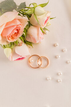 Romantic wedding rings with rose bouquet and pearl flatlay