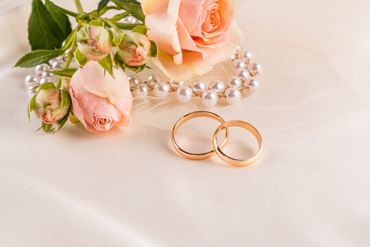 Wedding rings with rose and pearls on soft background