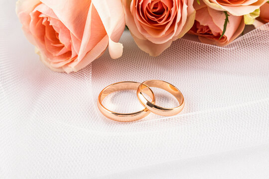 Gold wedding ring pair with rose bouquet on bridal veil