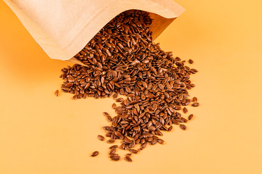 Flax seed spilling from paper bag on pastel background