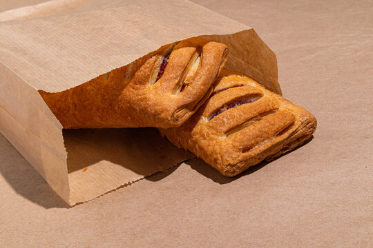 Fresh bakery pastries in paper bag on neutral background