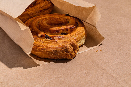 Fresh cinnamon pastry in paper bag on bakery counter top