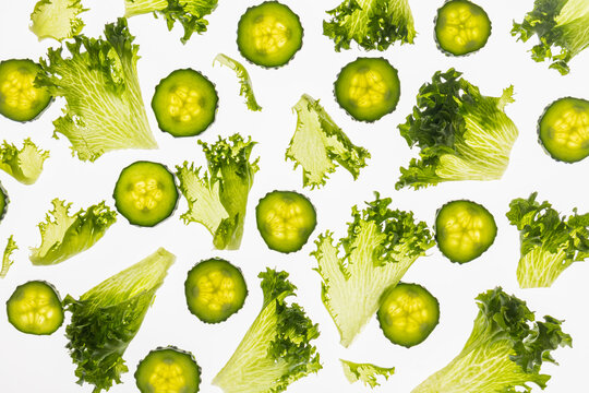 Fresh cucumber slices and lettuce pattern on white