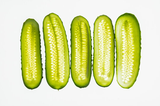 Sliced cucumber halves aligned on white background, top view