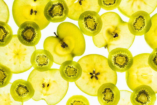 Backlit apple and kiwi slices pattern on white background