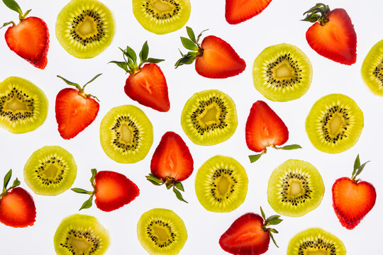 Flat lay of kiwi slices and strawberry halves on white