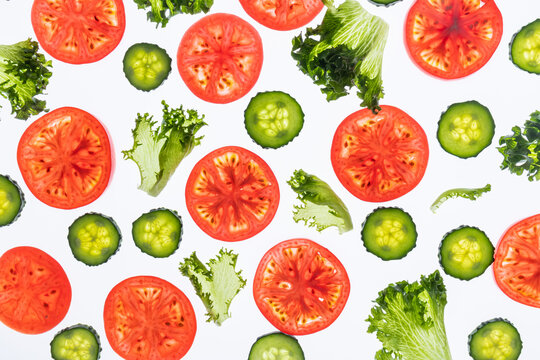 Fresh tomato and cucumber slices with lettuce on white