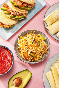 Tablescape of Latin American dishes on pink table, top view