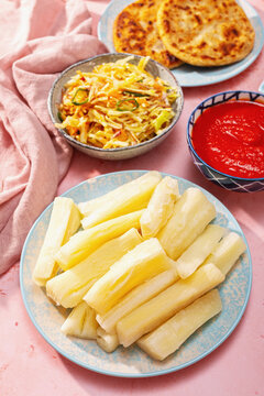 Boiled yuca with pupusas, curtido and salsa on table