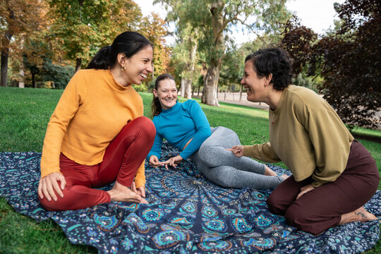 Women relax on blanket at outdoor spiritual retreat